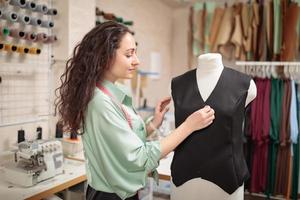 tailleur féminin, couturière, créateur de mode travaillant avec des vêtements sur mannequin dans un studio d'atelier