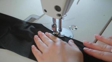 aiguille de machine à coudre en mouvement. gros plan de l'aiguille de la machine à coudre se déplace rapidement de haut en bas. le tailleur coud du tissu noir sur l'atelier de couture. photo