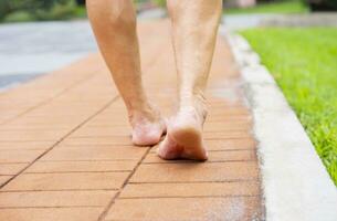 Sénior homme pieds nus en marchant sur briques passerelle dans le parc photo