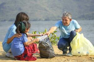 grand-père bénévole détient Plastique bouteille enseigner les enfants à séparé des ordures à le sable plage, collecte et séparé Plastique bouteille pour réutilisation, concept de environnement conservation, campagne, sensibilisation, soutien photo