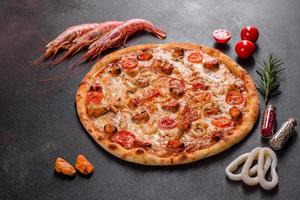 savoureuse pizza en tranches avec fruits de mer et tomate sur fond de béton