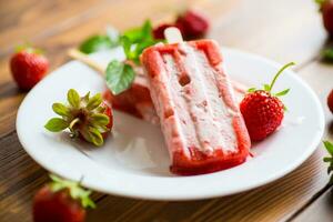 fait maison fraise la glace crème sur une bâton dans une assiette avec des fraises photo