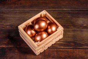 oeufs de pâques dans une boîte en bois cadeau sur fond de bois foncé photo