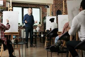 Sénior homme expérimenté artiste enseignement dessin Des classes à adultes, création positif apprentissage environnement dans art classe. groupe de diverse différent vieilli élèves entraine toi esquisse compétences ensemble photo