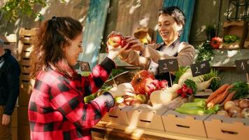 végétarien client choisir coloré pommes et des produits, à la recherche à biologique produire sur Les agriculteurs marché décrochage. femme affaires propriétaire vente Frais saisonnier des fruits et légumes à festival. photo