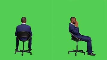 Jeune homme d'affaire séance sur chaise et en attendant, portant formel Bureau costume et posant plus de plein corps écran vert toile de fond. Masculin Commencez employé sentiment optimiste dans studio, élégant ouvrier. photo