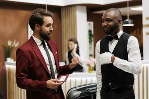 Hôtel Personnel portion client à trouver chambre, assurer agréable rester et porter bagage pour lui. homme d'affaire sur travail Voyage en train de préparer pour A venir international conférence, vérification dans à station balnéaire. photo