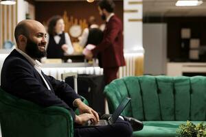 homme d'affaire attendre dans accueil lobby, portant élégant costume et en train de préparer à vérifier dans. ouvrier en voyageant sur affaires voyage à assister exécutif planche réunion à international quartier général. photo