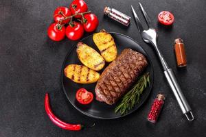 steak de faux-filet avec pommes de terre, oignons et tomates cerises photo