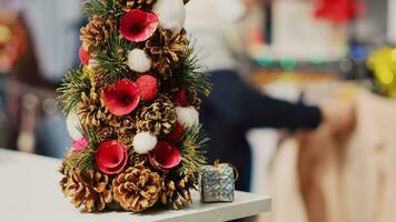 extrême proche en haut coup de de fête miniature Noël arbre orné avec pin cônes et fleurs séance sur Vêtements boutique compteur pendant hiver vacances saison. Noël décor dans mode boutique photo
