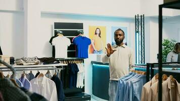 africain américain client en utilisant hologramme dans boutique à vérifier Nouveau Vêtements boutique marchandise avec augmenté réalité. Masculin client à la recherche à holographique images, artificiel intelligence. photo