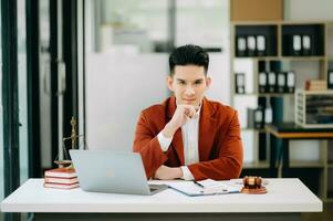 Justice et loi concept .asiatique Masculin juge dans une salle d'audience sur table et conseiller travail dans moderne bureau. à la recherche à caméra photo