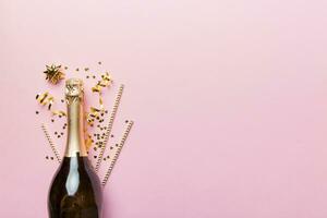 bouteille de Champagne avec des lunettes et coloré confettis sur coloré Contexte. Haut vue écorcher allonger photo