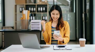 les femmes d'affaires asiatiques sont ravies et satisfaites du travail qu'elles font sur leur tablette, leur ordinateur portable et en prenant des notes au bureau. photo