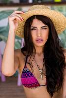 proche en haut portrait de sensuel femme dans paille chapeau avec parfait longue Cheveux posant dans plage bar. été ambiance. photo