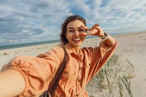 une femme dans un Orange robe et chapeau sur le plage photo