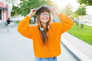 content étudiant fille avec une livre sur sa tête ayant amusement Extérieur après cours. photo