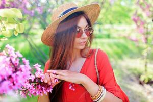 Extérieur printemps proche en haut portrait de romantique brunette femme profiter fleurs dans ensoleillé épanouissement jardin. photo