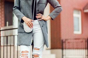 mode détails de élégant femme. gris manteau, blanc jeans . photo