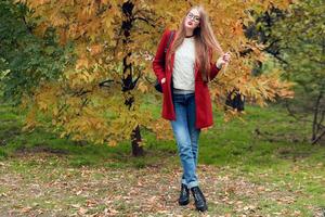 plein la taille l'automne mode image de agréable femme dans rouge élégant manteau et tricoté chapeau dans l'automne parc. photo