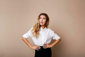 surprise affronter. blond femme dans décontractée tenue permanent plus de beige Contexte. sorti fille à la recherche à caméra. photo