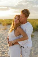 européen magnifique couple embrassement contre le coucher du soleil tandis que sortir ensemble sur le plage. proche en haut portrait de homme et femme ensemble, à la recherche à chaque autre. photo