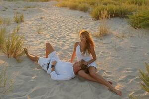 été portrait de Jeune élégant couple séance sur le plage sur ensoleillé soir . photo