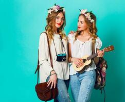 studio mode de vie portrait de deux jolie Jeune blond content les filles ayant amusement. fabrication des photos dans branché style sur rétro caméra, portant élégant ancien boho tenues et fleurs couronne. printemps.