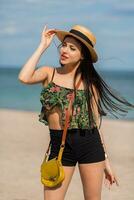 Extérieur été mode de vie portrait de parfait en forme souriant femme avec parfait corps ayant amusement sur le tropical plage portant paille chapeau. brillant couleurs. content ambiance. photo