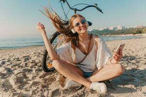 Jeune attrayant blond souriant femme sur vacances séance sur plage photo