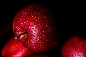 pomme rouge juteuse fraîche avec des gouttelettes d'eau sur fond sombre photo