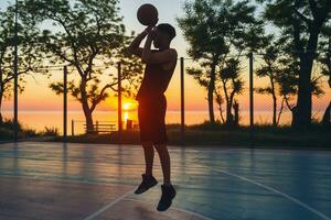 noir homme Faire des sports, en jouant basketball sur lever du soleil, sauter silhouette photo