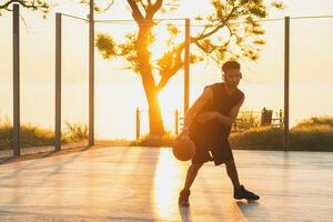 noir homme Faire des sports, en jouant basketball sur lever du soleil, actif mode de vie, ensoleillé été Matin photo
