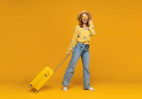 une femme dans des lunettes de soleil et une Jaune chemise est en portant une valise photo