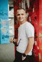 sur de soi Jeune homme. Beau caucasien modèle dans Urbain été mode de vie portrait. élégant Jeune homme Urbain été mode de vie portrait. caucasien homme avec une branché Urbain Regardez photo