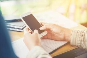 les mains d'une femme d'affaires travaillant sur un téléphone intelligent et des informations commerciales photo