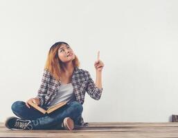 jeune femme hipster tenant des livres et pointant vers le haut sur blanc isolé. photo