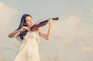 belle femme debout jouant du violon dans le pré photo