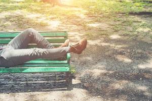 mec hipster allongé sur un banc avec un jean et des chaussures de chamois marron.