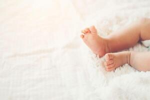 jambes de bébé nouveau-né sur un lit blanc. photo