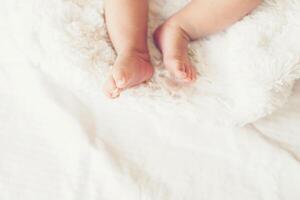 jambes de bébé nouveau-né sur un lit blanc. photo