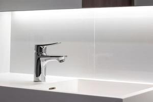 nouveau robinet en acier inoxydable sur un évier de lavabo propre dans la salle de bain photo