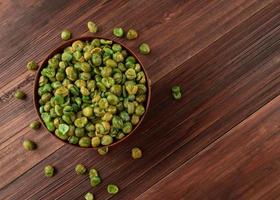 vue de dessus des pois verts salés dans un bol en bois sur la table, mise à plat photo