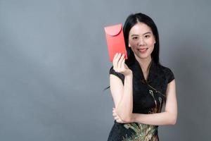 une femme asiatique porte une robe traditionnelle chinoise avec un paquet rouge photo