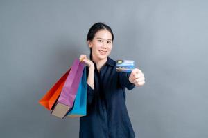 belle femme asiatique avec des sacs à provisions et montrant une carte de crédit
