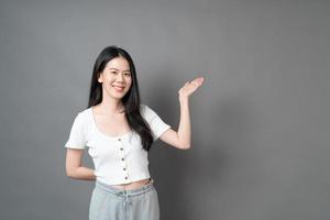 femme asiatique avec le visage souriant et la main présentant sur le côté photo