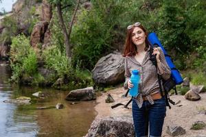 touriste femme avec un sac à dos un fond de montagne et de rivières photo