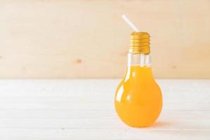 jus d'orange en forme de lampe verre sur bois photo