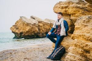 homme avec un sac à dos debout près d'un rocher contre une mer magnifique photo