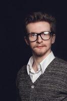 Portrait de jeune homme avec des lunettes sur fond noir photo